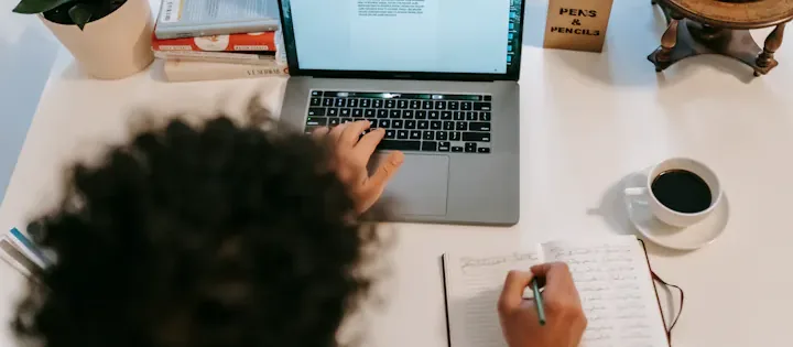 Writer using a portable computer at a table, working on manuscript and book launch marketing strategy